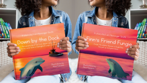Images of the books titled Finn's Friend Fungie and Down by the Dock, held by two girls