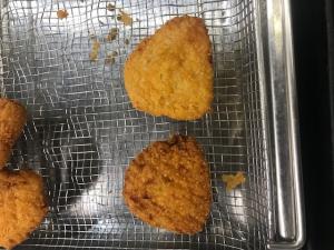 Pictures of two chicken burgers. One is darker than the other. The lighter color is from a fryer with OiLChef