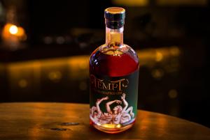 A  bottle of Tempt Gin at a nightclub with low sexy lighting.