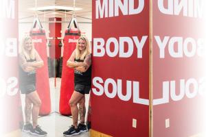 Christina Rondeau leaning on a wall that says Mind, Body, Soul