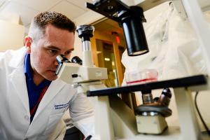a researcher looks into a microscope