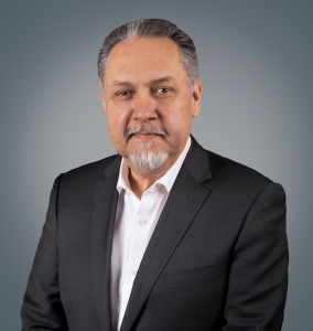 This photograph is a portrait shot of Armando Contreras in a suit. He is the president and chief executive officer of United Cerebral Palsy.