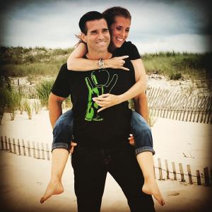 Seth holding Allison piggyback on his back for a beach Rockin Wellness photoshoot, August 2016