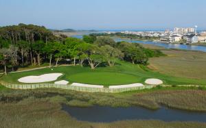 The 12th hole on Tidewater golf course is a par 3 where the tee shot is almost entirely over water. You can see the Cherry Grove homes and salt water march in the background.
