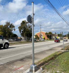 Photo of Red light camera enforcement on side of road monitoring traffic as cars drive by