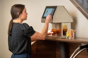 Bartender using Easybar Automated Cocktail Station to make a Long Island Iced Tea by selecting the drink on a touchscreen