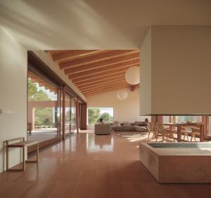 The main living and gathering area features incredible vaulted ceilings with exposed beams, a fireplace, and floor to ceiling glass doors on both sides.