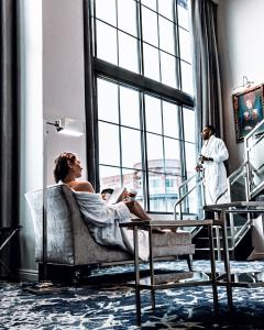 Chris and Reg Travel is a married, racially diverse content creation and social influencing team that focuses on the travel and lifestyle industry Chris and Reg are both enjoying morning coffee in a beautiful loft style hotel suite that that has 20feet tall floor to ceiling windows. Chris is sitting in a chaise lounge wearing a white robe off off the right shoulder. Reg is also wearing a white rob