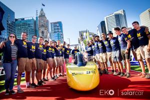 The University of Michigan Solar Car Team celebrate with their car after finishing third at the Bridgestone World Solar Challenge 2019.