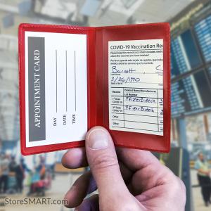 A hand holding red folding card holder. Inside the holder is a vaccine card and a medical appointment card.