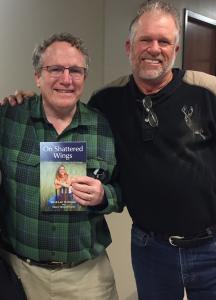 Jim Dultmeier (right) presents a book about his family's grief journey to Dr. James Hamilton, the surgeon who tried to save Jim's daughter's life 19 years ago