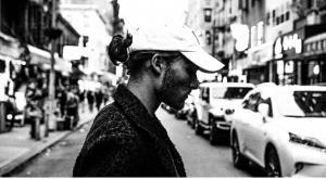 Alex Silver wearing white baseball cap crossing a busy street.
