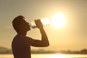 Employee hydrates himself to prevent heat illness while working during high temperatures