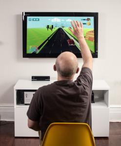 A patient playing the serious therapeutic videogame MindMotion GO is seen raising his hand during an engaging neurorehabilitation exercise.