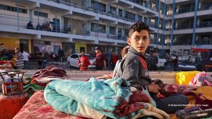 A Palestinian boy who fled his home due to Israeli air and artillery strikes sits on a mattress at a school in Gaza City. Photo: Mohammed Abed/AFP via Getty Images