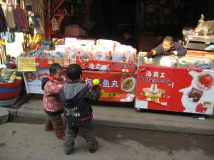 Three boys playing with water guns in Shanghai storefront