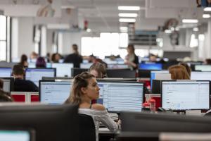 Photograph of outsourced customer support company,  Ventrica's bright, open-planned office in Southend on Sea. A female contact centre advisor is central in the photo, sits in front of two computer screens, looking to the right.