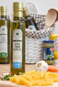 Artem Oliva's early harvest extra virgin olive oil is best for all types of hot or cold meals. This image is showing premium extra virgin olive oils in the kitchen with some pasta and garlic in the scene.