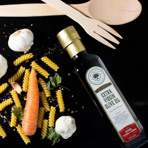 Artem Oliva's extra virgin olive oil is best for all types of hot or cold meals. This image is showing premium extra virgin olive oils on a blackdrop with some pasta, garlic and carrot.
