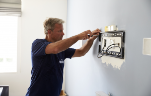 A Mila technician installing a wall mount for a smart TV.