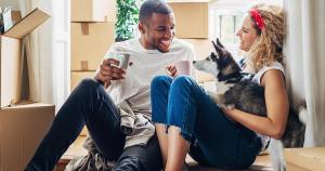 Couple with dog sitting among moving boxes in a home