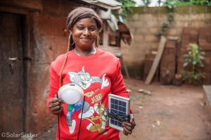 A Solar Sister customer in Tanzania hold her new solar lamp and panel.