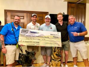 5 men, 2 with service dogs hold up a large check for $35,000