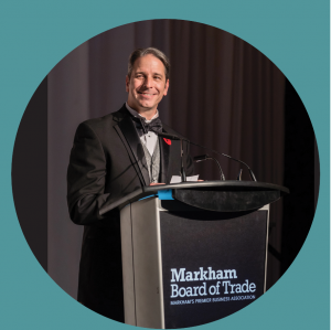 Chris_Collucci_MBT_Markham-Board-of-Trade-President-and-CEO-Wearing-Tuxedo-Speaking-At-Event-Standing-at-Speaker-Podium