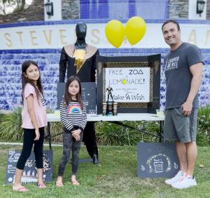 Leialoha Batgirl Carlos 8, and Kara Zor-El Carlos, 6, are shifting the balance of power in the lemonade stand universe by also offering ZOA in an effort to raise $100K for the Make-A-Wish Foundation at BlackAdamFitnessChallenge