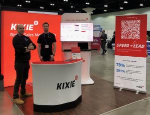 Two Kixie reps standing in the Kixie conference booth, promoting their sales calling tool with local presence and auto-dialer/power dialer
