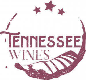 Tennessee Wines logo in red featuring a circular red wine stain, the likeness of a vineyard, three stars at the top and the words "Tennessee Wine" typed inside of the wine stain.